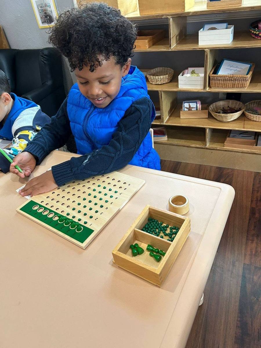 Un niño sonriente trabaja con el tablero de multiplicación