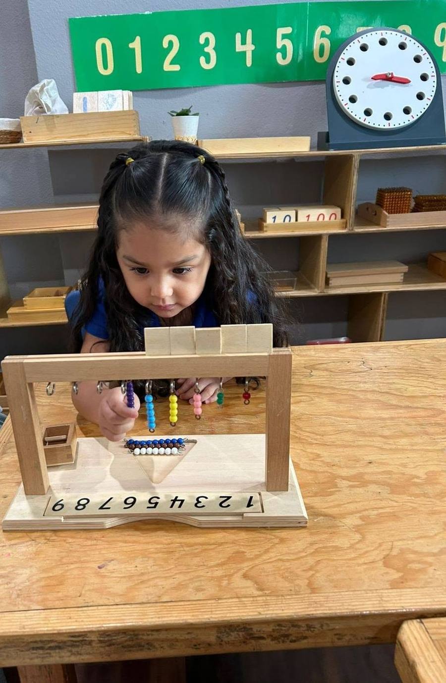 Una niña cuenta con la escalera de perlas de colores