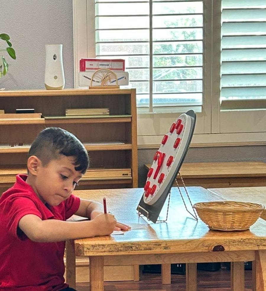 Un niño anota la hora de un reloj didáctico