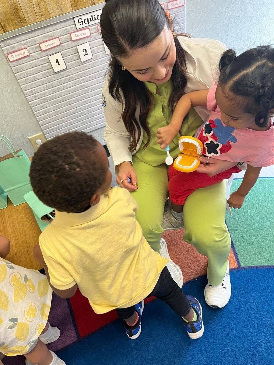 A visiting dentist shows toddlers how to brush teeth