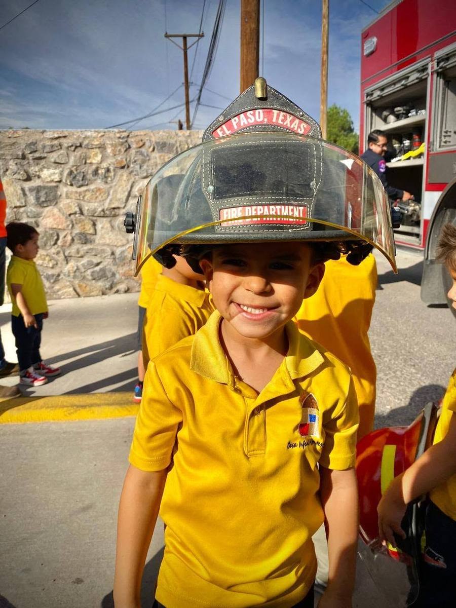 A smiling child wears an El Paso firefighter’s helmet