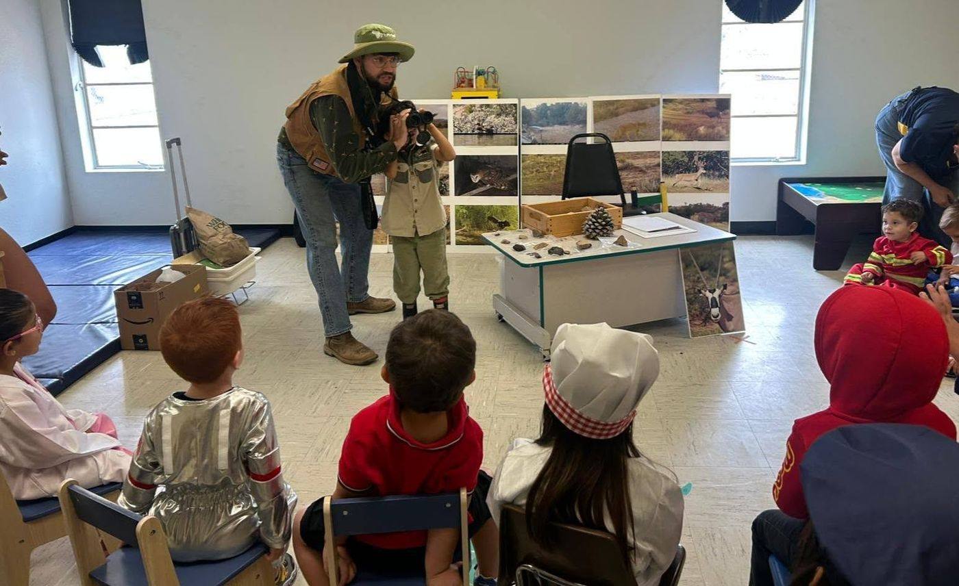 A visiting naturalist shows a child how to use binoculars