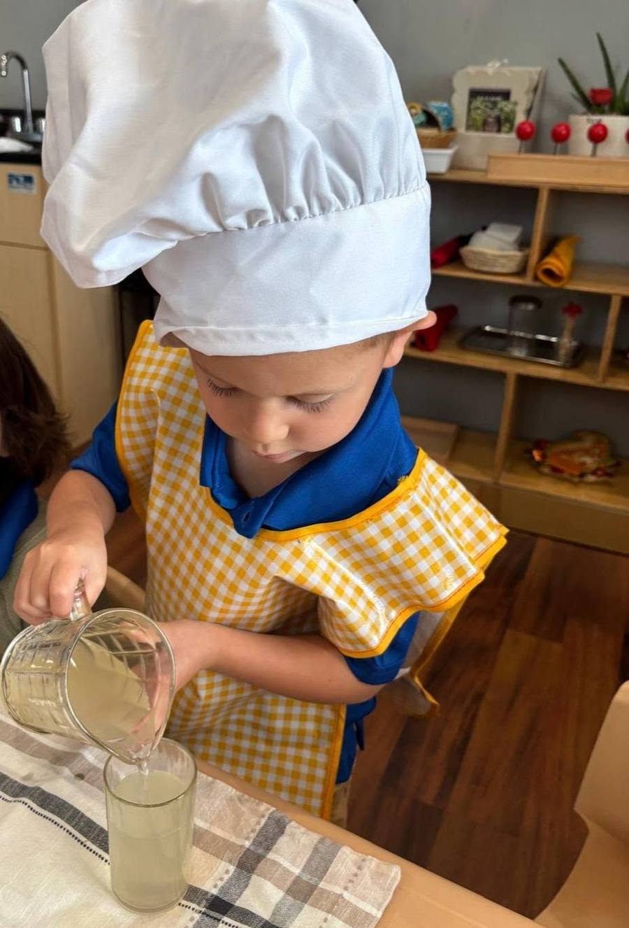 Un niño con gorro de chef sirve limonada con cuidado